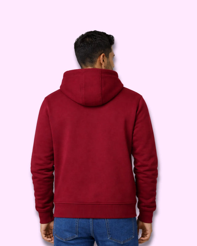 Man wearing a maroon hoodie on a light pink background