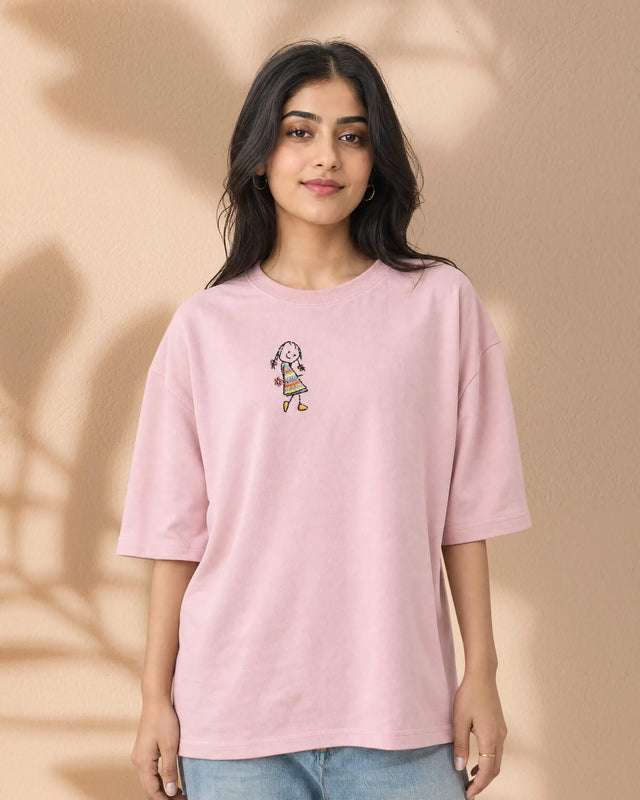 Person wearing a Baby Pink French Terry t-shirt with a small graphic on a beige background