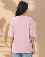 Person wearing a pink t-shirt against a beige background