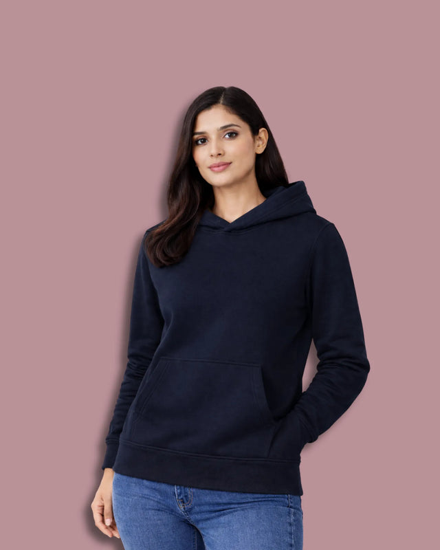 Woman wearing a navy blue hoodie against a pink background