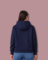 Woman wearing a navy blue hoodie on a pink background