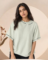 Woman wearing a light green t-shirt with text on a beige background