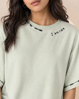 Person wearing a light green t-shirt with 'I am rare' text on a neutral background