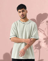 Man wearing a light green t-shirt with text design against a pink background