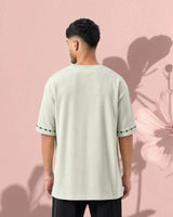 Man wearing a light green t-shirt against a pink background