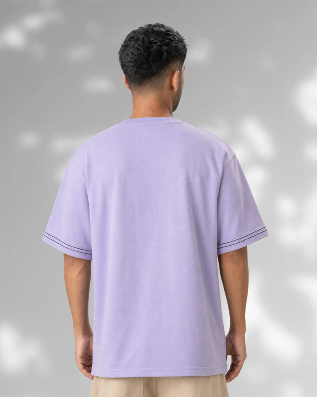 Person wearing a light purple t-shirt against a gray background