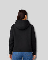Person wearing a black hoodie from behind on a gray background
